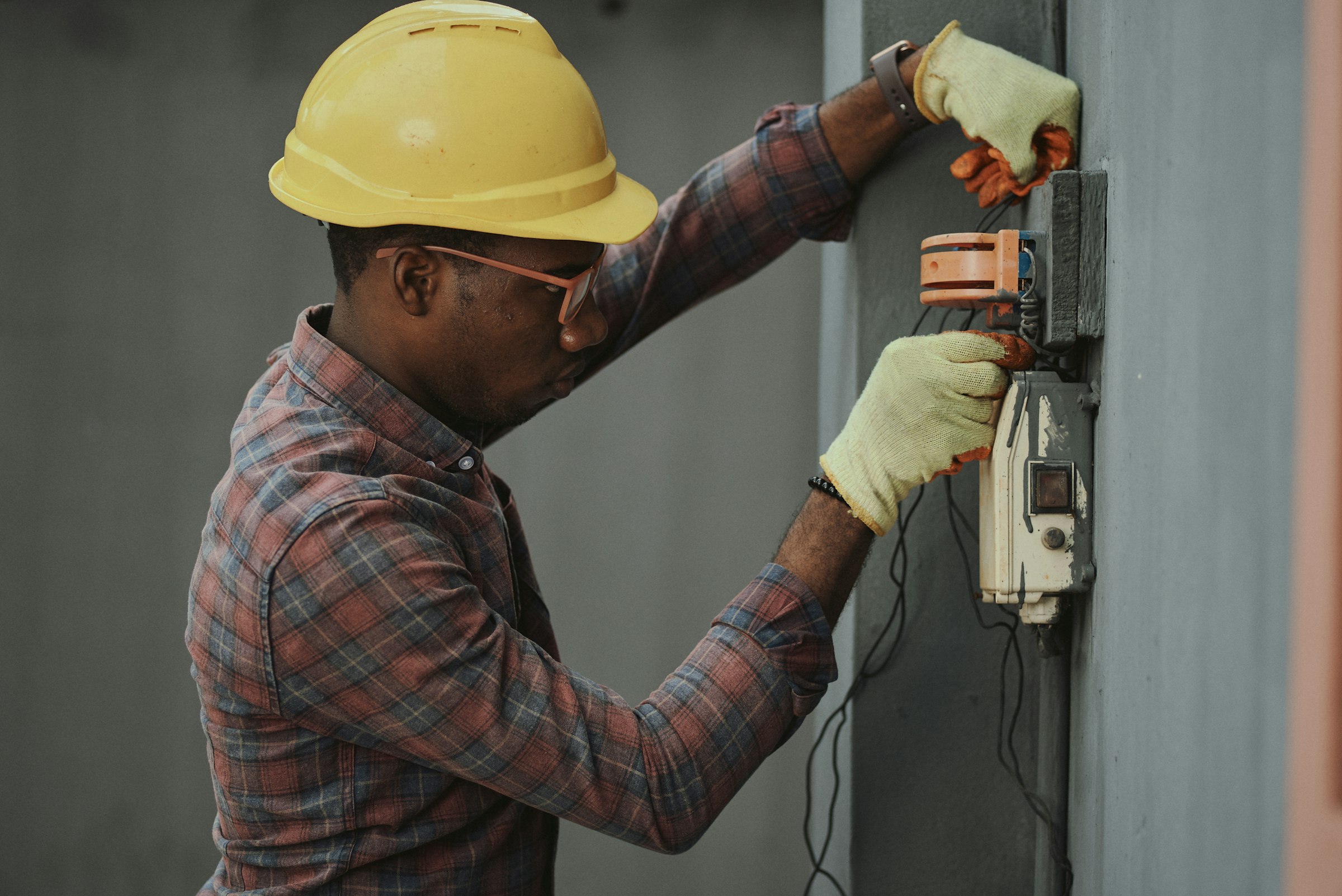 Electrician in a hard hat working on an electrical fitting